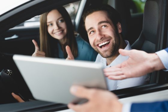 Pareja sonriendo en su auto por contar con una buena aseguranza de carro.