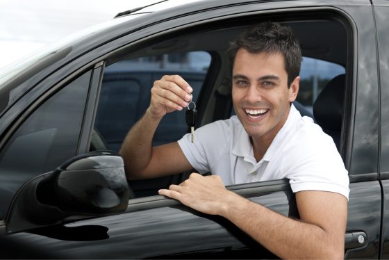 Conductor feliz sosteniendo la llave de su vehículo al obtener su seguro de auto.