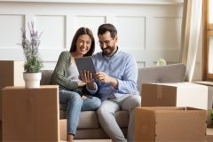 Pareja hispana sentada en sillon viendo una tableta.