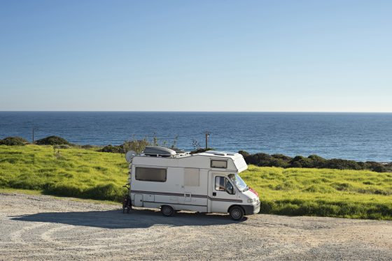 Casa móvil estacionada de lado al frente de oceano.