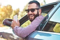 Hombre adulto sonriendo en la ventana de su auto.