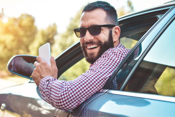 Hombre adulto sonriendo en la ventana de su auto.