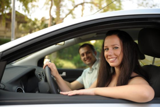 Una joven sonriente conduciendo un automóvil asegurado.