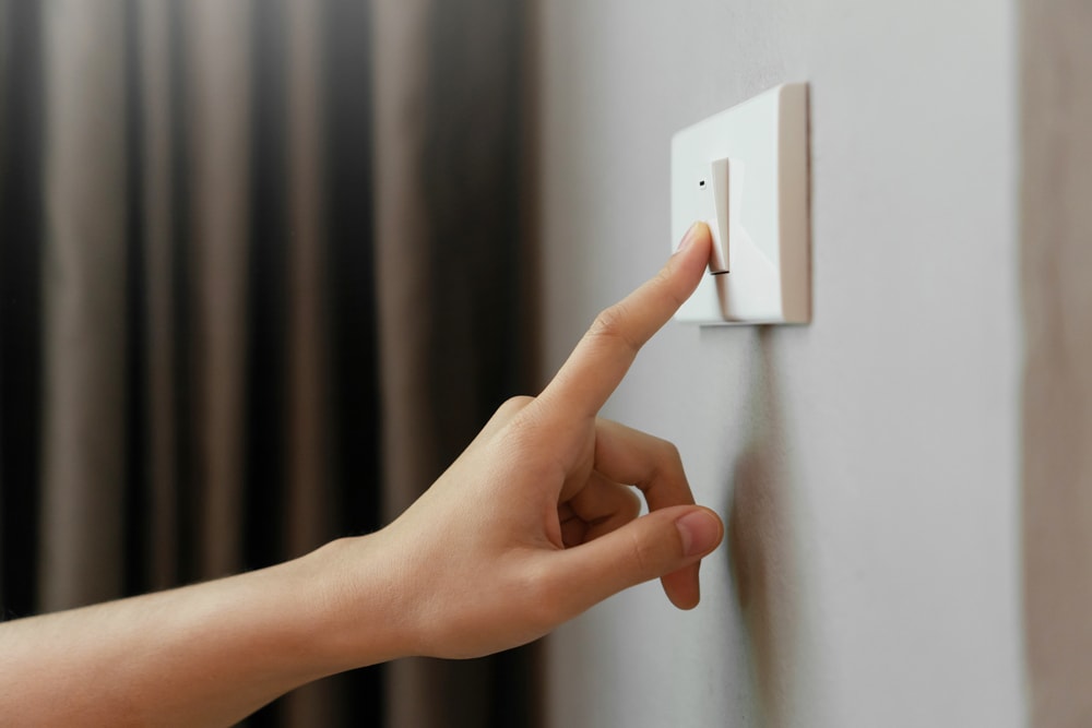Persona presionando enchufe de luz para tener ahorro de nergía en su casa