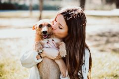 Joven mujer abrazando y besando a perrito tras adopción de mascotas en San Diego