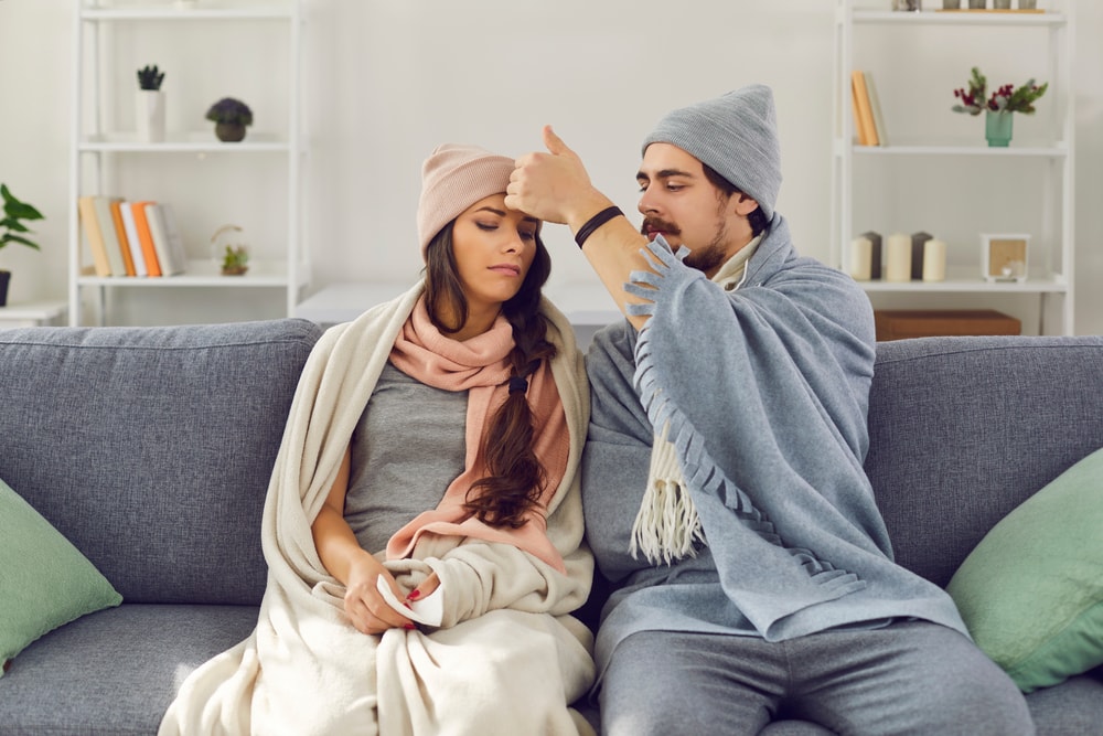 Hombre y mujer cuidandose uno al otro de enfermedades de invierno