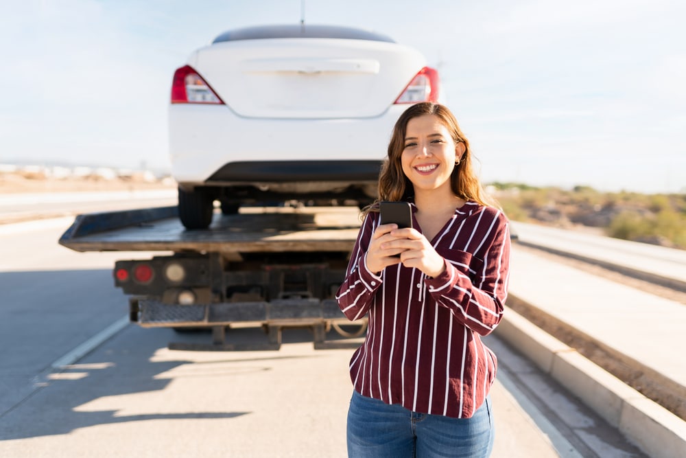 Mujer sonriente tras descubrir qué hacer si te quedas sin frenos en un carro automático con Cost- U-Less