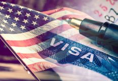 Tipos de visas para ingresar a los Estados Unidos sobre la bandera y un boligrafo