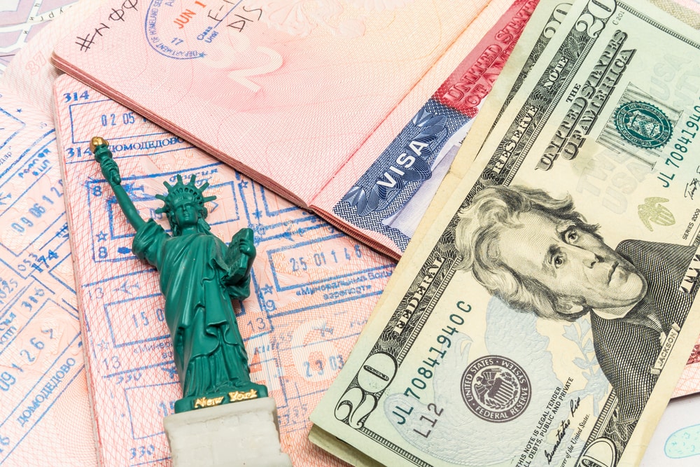 Documentos, dólares y una figura de la estatua de la libertad de alguien que se prepara para aplicar a los tipos de visas para ingresar a los Estados Unidos