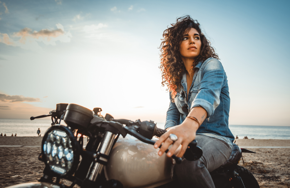 Mujer latina sobre motocicleta pensando en cómo asegurar tu moto