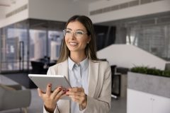 Mujer profesional usando una tablet en oficina, simbolizando la solicitud en línea de un permiso de trabajo.