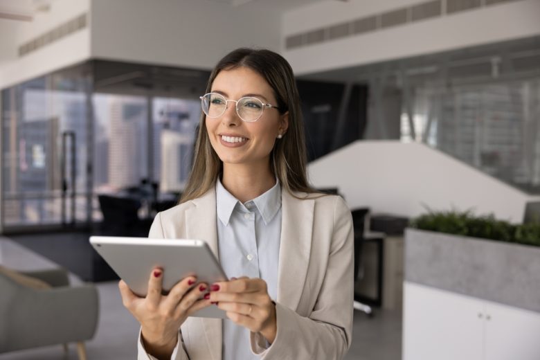 Mujer profesional usando una tablet en oficina, simbolizando la solicitud en línea de un permiso de trabajo.