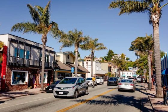Calle con autos y palmeras en una ciudad de California, relacionada con pagar la placa del carro en línea en California.