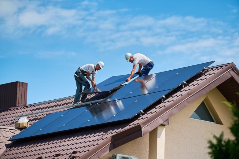 Hombres instalando paneles solares en una casa - Seguro de hogar cubre paneles solares - Cost-U-Less