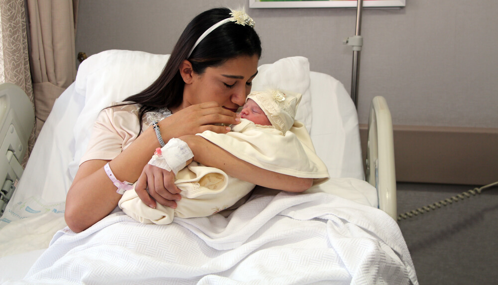 Madre con su recién nacido en el hospital, recibiendo atención médica y orientación gracias a su seguro de salud