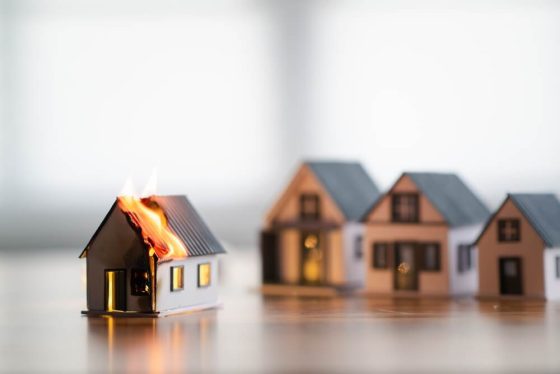 Casa en llamas junto a otras viviendas, ilustrando zonas de riesgo en California por incendios.