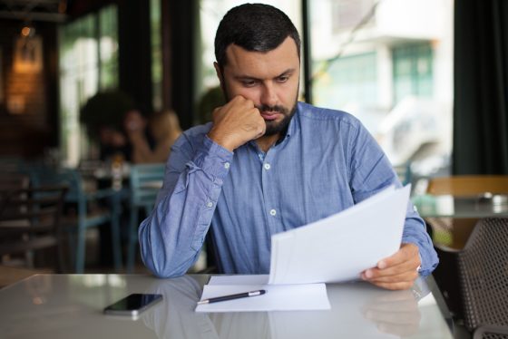 Hombre preocupado revisando documentos tras recibir aviso de que la aseguradora no renueva tu póliza de auto en California.