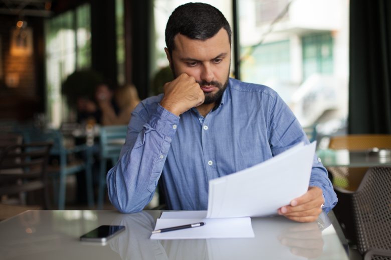Hombre preocupado revisando documentos tras recibir aviso de que la aseguradora no renueva tu póliza de auto en California.