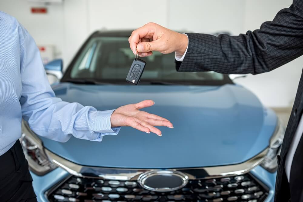 Entrega de llaves entre vendedor y comprador frente a un auto, representando el seguro de auto si vendes tu vehículo.