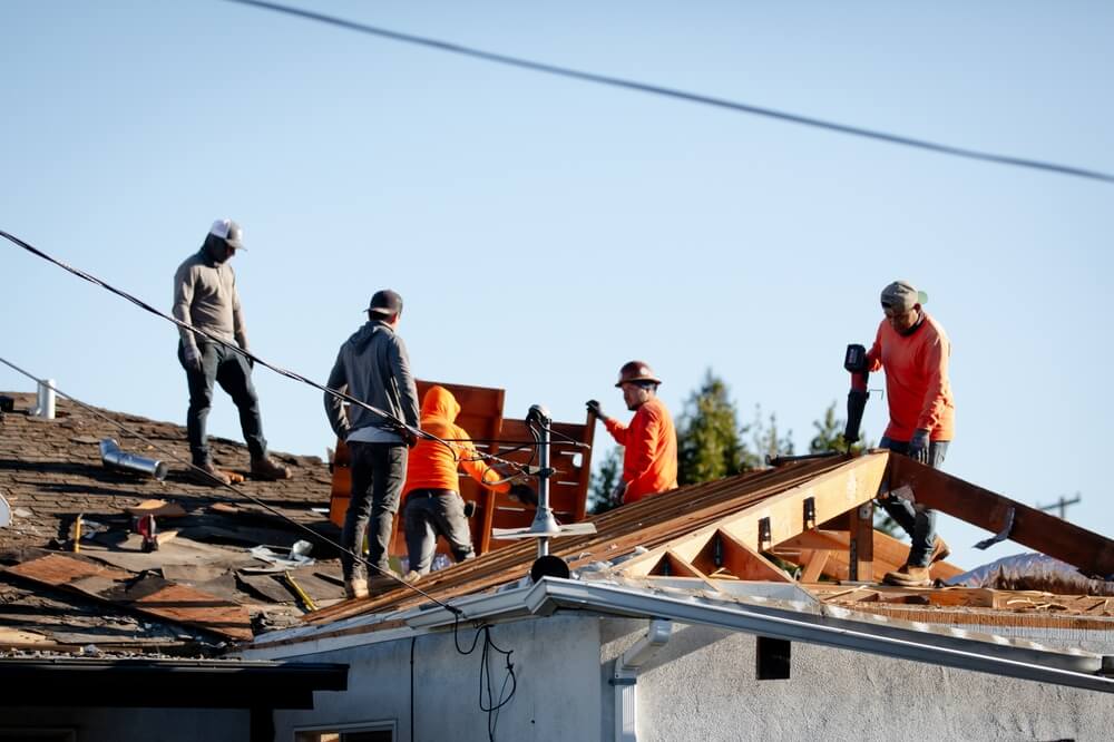Trabajadores reparan techo de vivienda, ejemplo de seguro de hogar durante remodelación en California cubriendo riesgos de construcción