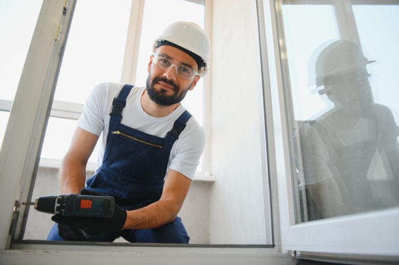 Trabajador repara una ventana en casa, ejemplo de un reclamo pequeño en tu seguro de hogar