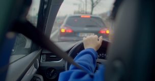 Persona conduciendo un automóvil en tráfico urbano, relacionado con seguro de auto con licencia suspendida y requisitos para volver a conducir legalmente.
