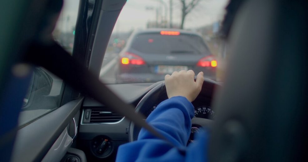 Persona conduciendo un automóvil en tráfico urbano, relacionado con seguro de auto con licencia suspendida y requisitos para volver a conducir legalmente.