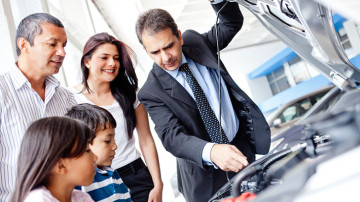 Familia recibiendo indicaciones de un especialista en el mantenimiento de vehículos
