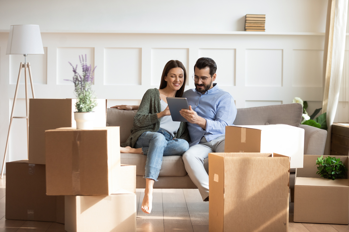 Pareja hispana sentada en sillon viendo una tableta