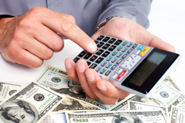 Mano con una calculadora y el conceptoo de ahorrar dinero con billetes