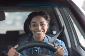 Mujer hispana conduciendo y sonriendo