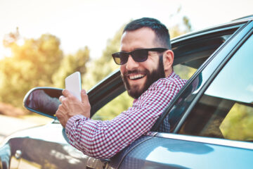 Hombre adulto sonriendo en la ventana de su auto