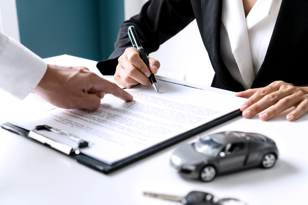 Mujer firmando el contrato de su póliza de seguro de auto
