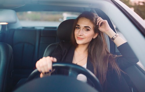 Mujer hispana sonriendo en su auto mientra maneja