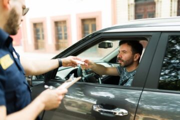 Hombre caucásico siendo detenido por la policia por infringir las normas de tránsito