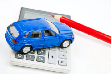 carro de juguete simbólico a un seguro de auto encima de una calculadora