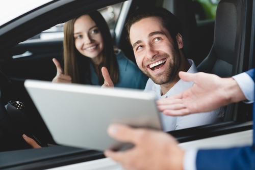Pareja sonriendo en su auto por contar con una buena aseguranza de carro