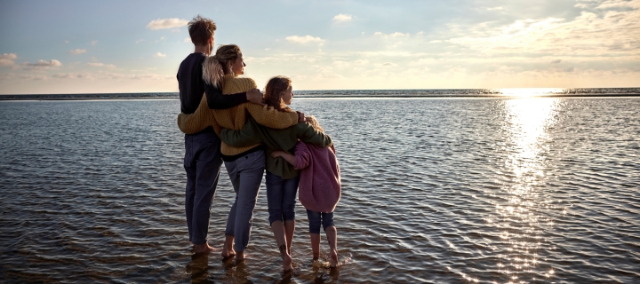 Familia abrazada mirando el atardecer en el mar