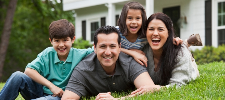 Familia sonriendo feliz en el jardín de su casa