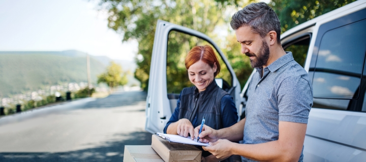 Mujer firmando entrega de paquetes a mensajero