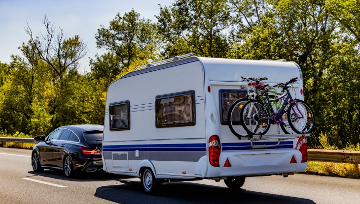 Vehículo protegido con el mejor seguro para remolque de viaje, con bicicletas en la parte trasera