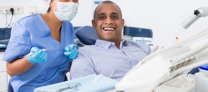 Hombre latino sonriendo junto a su dentista por tener seguro dental barato en California.